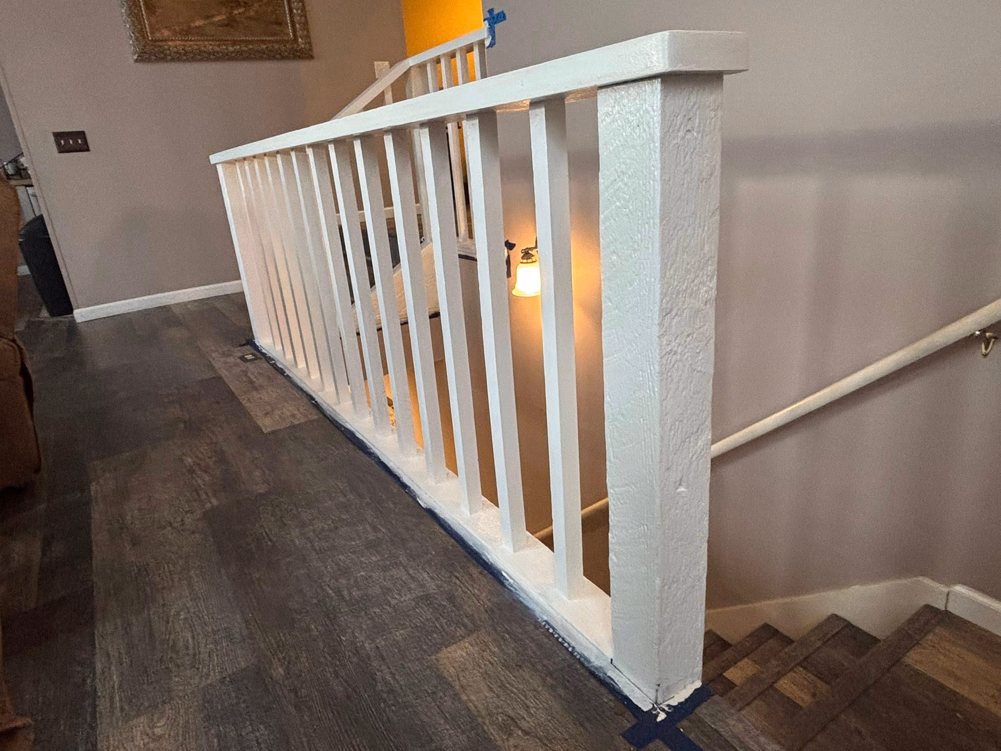 Interior staircase with white wooden railing and dark wood floor in a home setting.